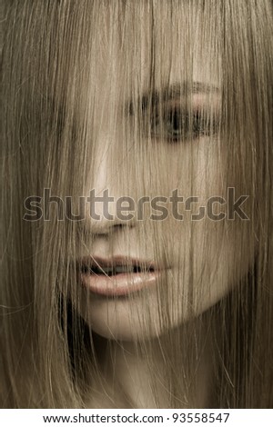 close up of a young and cute blond woman with hairstyle and hair covering her face