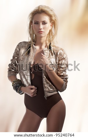 blond beautiful youg woman with golden earrings with hair style on light beam background