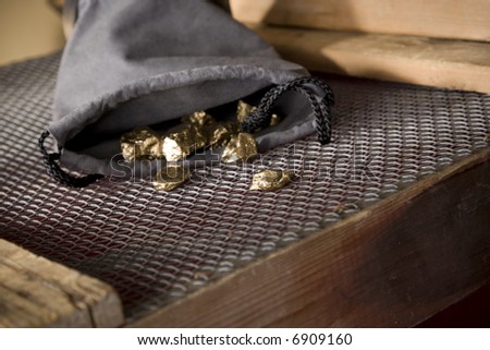 Gold nuggets spilling from a leather pouch. Riches. Wealth.