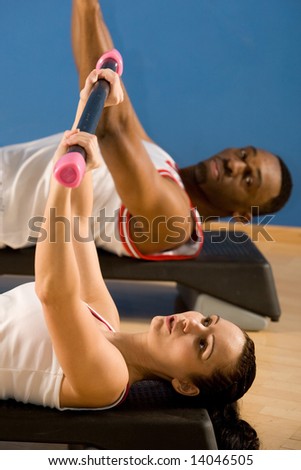 Young couple, attractive female, handsome male doing fitness exercises in the gym