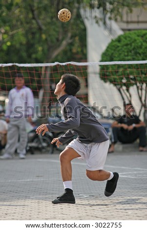 Man heads the ball in a game of Sepak Takraw