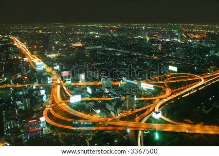 stock photo : Busy road intersection in the heart of downtown Bangkok, shot at night showing car headlight trails
