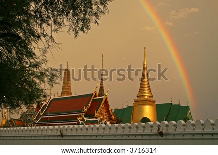 A storm just before sunset produces a dramatic rainbow against dark clouds over the Grand Palace and Wat Phra Kaeo in Bangkok.