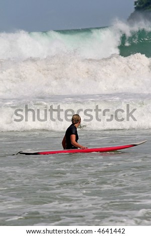 A surfer girl watches the huge waves approaching at Phuket in thailand