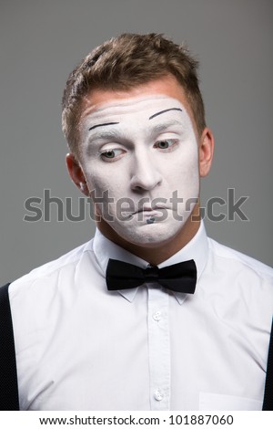 Face mime close-up emotions of confusion, black bow tie, theatrical makeup, isolated on a gray background