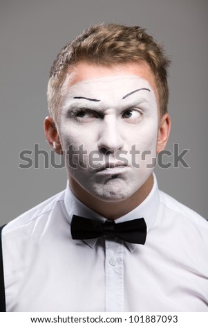 Face mime close-up, listens, black bow tie, theatrical makeup, isolated on a gray background