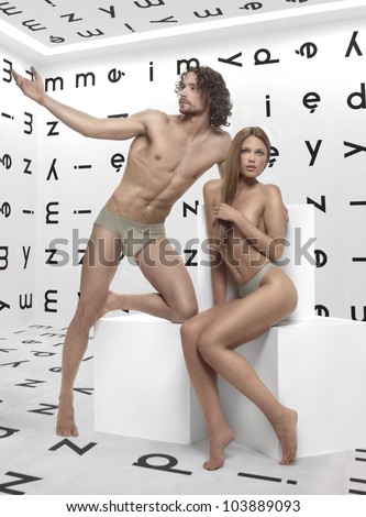 beautiful man and woman Adam and Eve, posing in the room with the alphabet on the walls of the white cubes