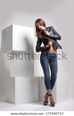 girl in black leather jackets, biker jacket posing in studio on large white cubes