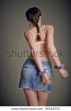 beautiful young girl in a denim skirt with handcuffs