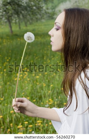 Young girl in a meadow with dandelion in the hands