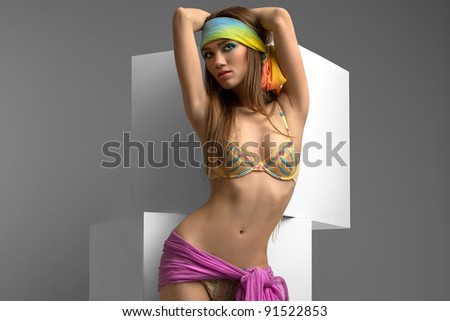 sexy girl in a bikini with a bright scarf on her head posing in studio