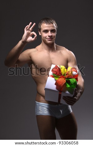 A young strong muscular man with a beautiful gift box and ribbon