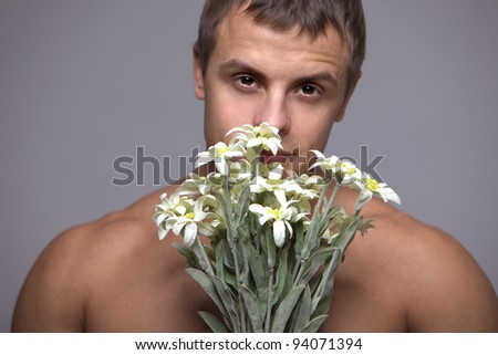 A young strong muscular man with a bouquet of flowers in his hands