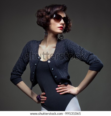 Luxury Fashion model, a beautiful woman posing in studio on gray background with glasses from the sun