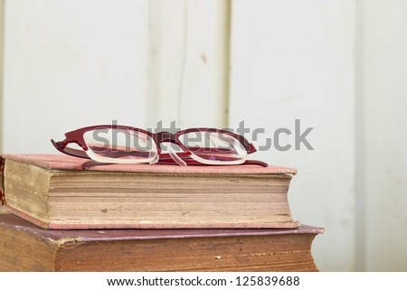 Closeup stack of old book pages texture with eye glasses.