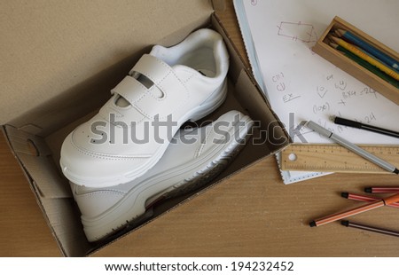 Pair of sneakers in shoe cardboard box on student table.