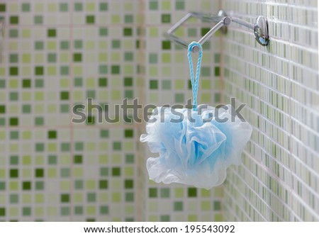 Blue Fiber Scrub hanging on the rail in the bathroom with green tiles.