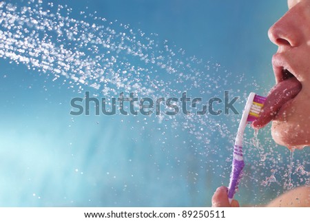 A young woman is brushing her tongue under the shower