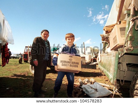 KUKES, ALBANIA, 17 APRIL 1999 --- A young  Kosovar Albanian refugee  returns to his camp in northern Albania with an aid packages distributed by the United States government.