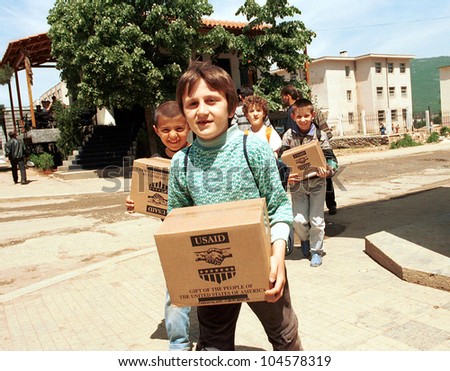 KUKES, ALBANIA, 18 APRIL 1999 --- Kosovar Albanian refugee children return to their camp in northern Albania with aid packages distributed by the United States government.