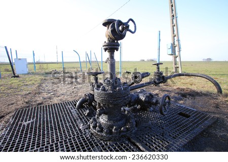 ARAD, ROMANIA - FRIDAY, DECEMBER 5, 2014: Oil leaks from a surface well head at a production field operated by OMV Petrom S.A, the largest gas and oil producer in Eastern Europe