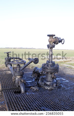 ARAD, ROMANIA - FRIDAY, DECEMBER 5, 2014: Oil leaks from a surface well head at a production field operated by OMV Petrom S.A, the largest gas and oil producer in Eastern Europe