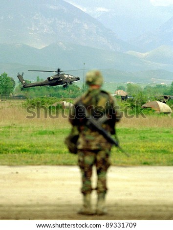 RINAS, ALBANIA - 21 APRIL: An United States  Army soldier watches the arrival of six U.S. Army Apache helicopters at a NATO-controlled airport outside the Albanian capital Tirana on April 21, 1999.
