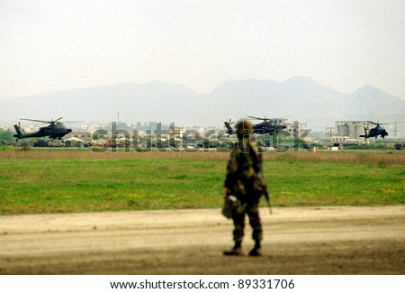 RINAS, ALBANIA - 21 APRIL: An United States  Army soldier watches the arrival of six U.S. Army Apache helicopters at a NATO-controlled airport outside the Albanian capital Tirana on April 21, 1999.
