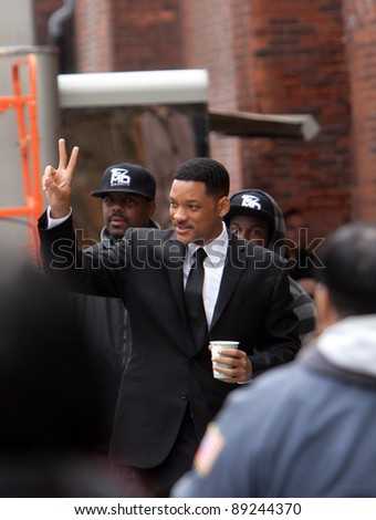 NEW YORK CITY - APRIL 15: Actor Will Smith, carrying a coffee cup, gives the peace symbol to some fans while working on the set of \