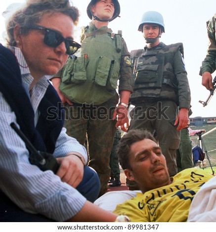 SARAJEVO, BOSNIA - APR 4: An aid worker, along with United Nations Protection Force (UNPROFOR)  comforts a Bosnian man wounded during the siege of Gorazde in amedivac facility in Sarajevo, Bosnia, on Monday,  April 4, 1994.