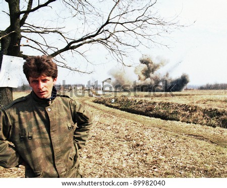 ODZAK, BOSNIA - MAR 24: A Bosnian Serb soldier talks while his house is blown up by United States Army troops in Bosnia as part of NATO\'s IFOR,  near Odzak, Bosnia, on Sunday, March 24, 1996. The house contained explosives