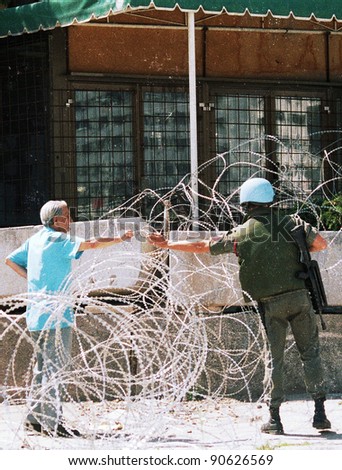 A French peacekeeper, in Bosnia with the United Nation\'s UNPROFOR, gives a local man a cigarette outside his barracks in Sarajevo, Bosnia, on Wednesday, Thursday, April 22, 1993.