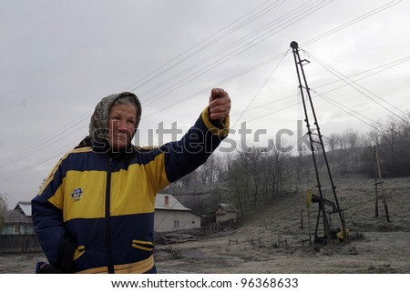 PLOIESTI , ROMANIA - NOV 8: An elderly woman gestures towards a field of pump jacks and oil storage tanks near Ploiesti, Romania, on Thursday, November 8, 2007.