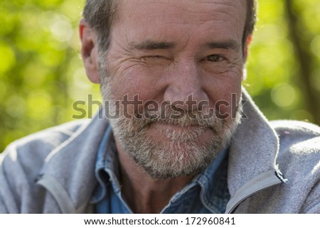 Closeup of an older man outside with one eye open