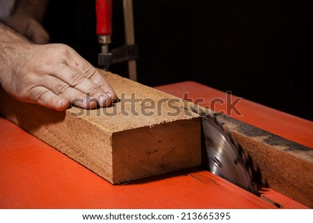 A craftsman cutting a plank of wood with circular table saw
