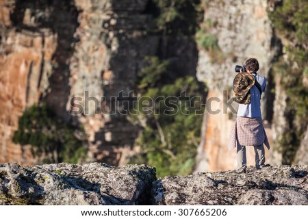 Young man taking a photo on the top of cliffs at Guartela Canyon, sixth largest canyon in the world in length - Tibagi/ Parana - Brazil