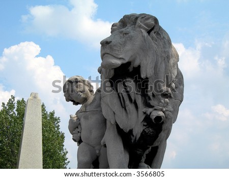Boy petting the lion. Famous statue on the Bridge of Alexander III in Paris in France.