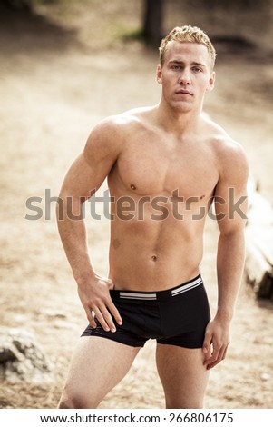 Portrait of a young sexy shirtless muscular man in underwear on a beach