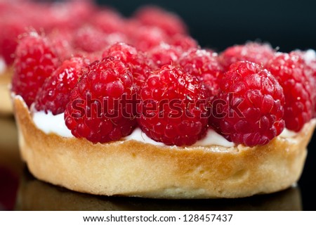 Small raspberry tarts on a black background.