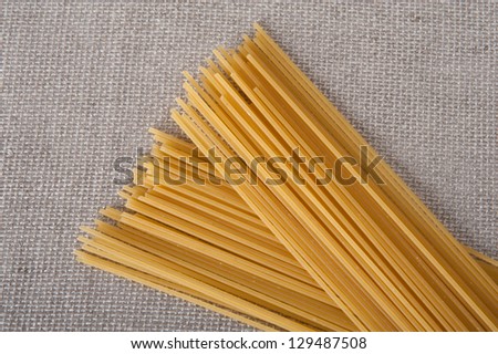 bunch of spaghetti on a beige table cloth ready to be cooked in an italian recipe