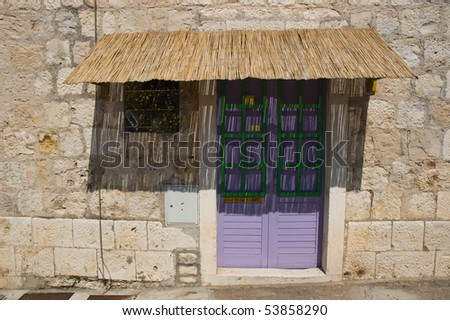 purple door protected from sun with straw roof