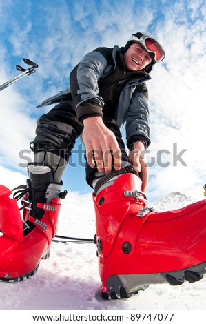 handsome male skier getting ready for skiing - fastening the boots