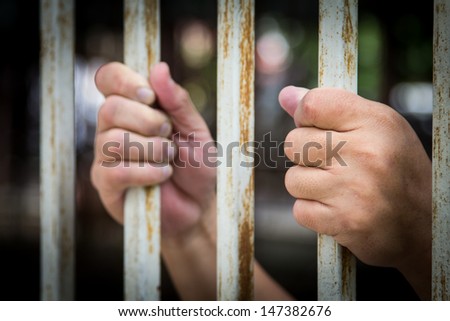 Man\'s hand holding the bars on both sides.