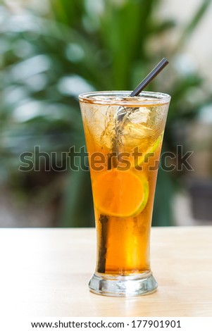 Glass of iced tea with lemon on a wooden table.