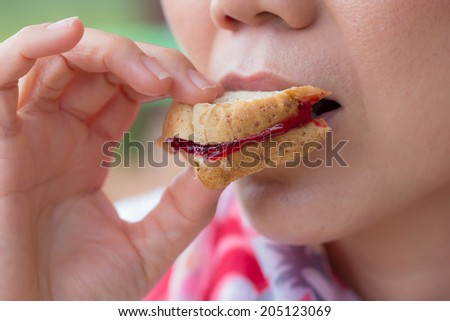 Asian woman eating bread with jam for breakfast.
