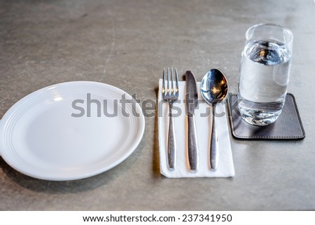 A dinner plate and knife, fork with glass on dining table