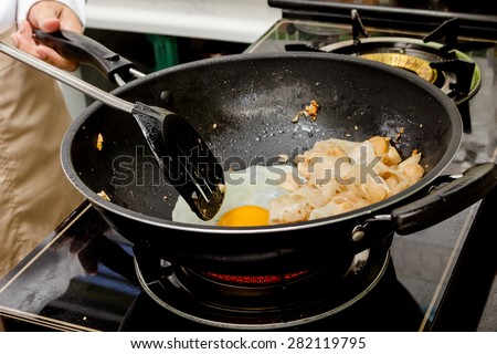 chef making stir-fried Noodles with pork in frying pan