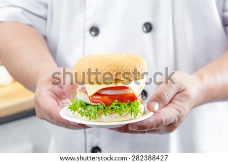 chef holding american cheese burger with fresh salad and french fries