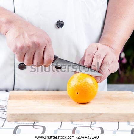 chef cutting orange on cutting boards
