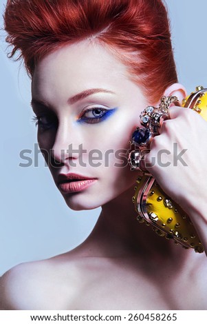 portrait of the beautiful young girl with light aristocratical skin, red hair and a stylish make-up, with a handbag clutch in hands